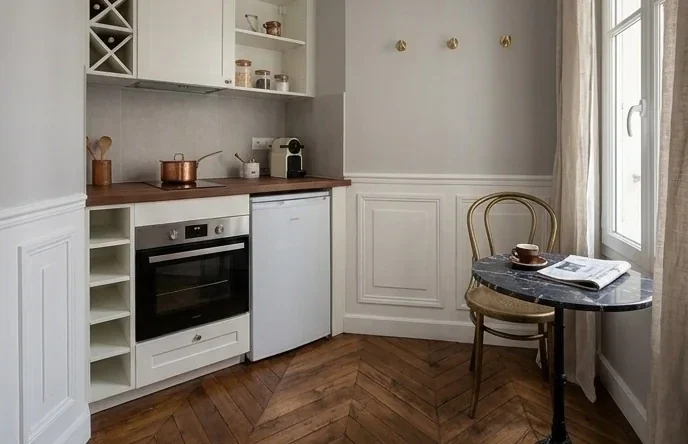 Cuisine ivoire avec coin repas, parquet chevrons et soubassement moulure