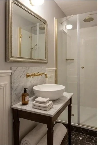 Salle de bain en marbre clair avec vasque, miroir laiton et douche a l'italienne